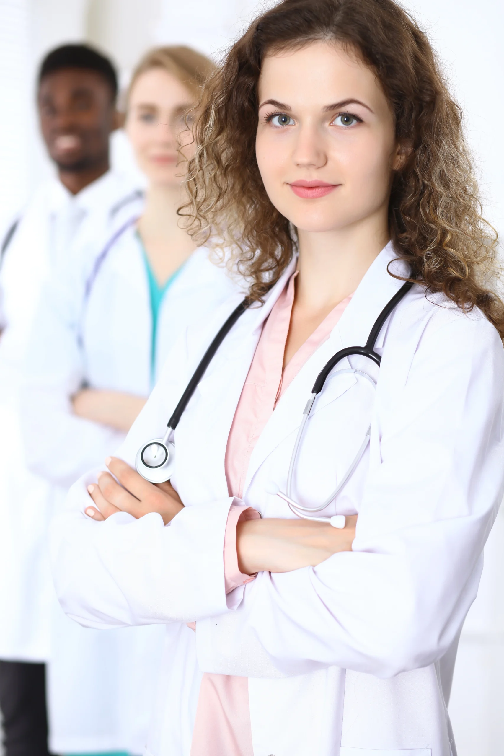 Three clinicians standing together in a bright clinical corridor